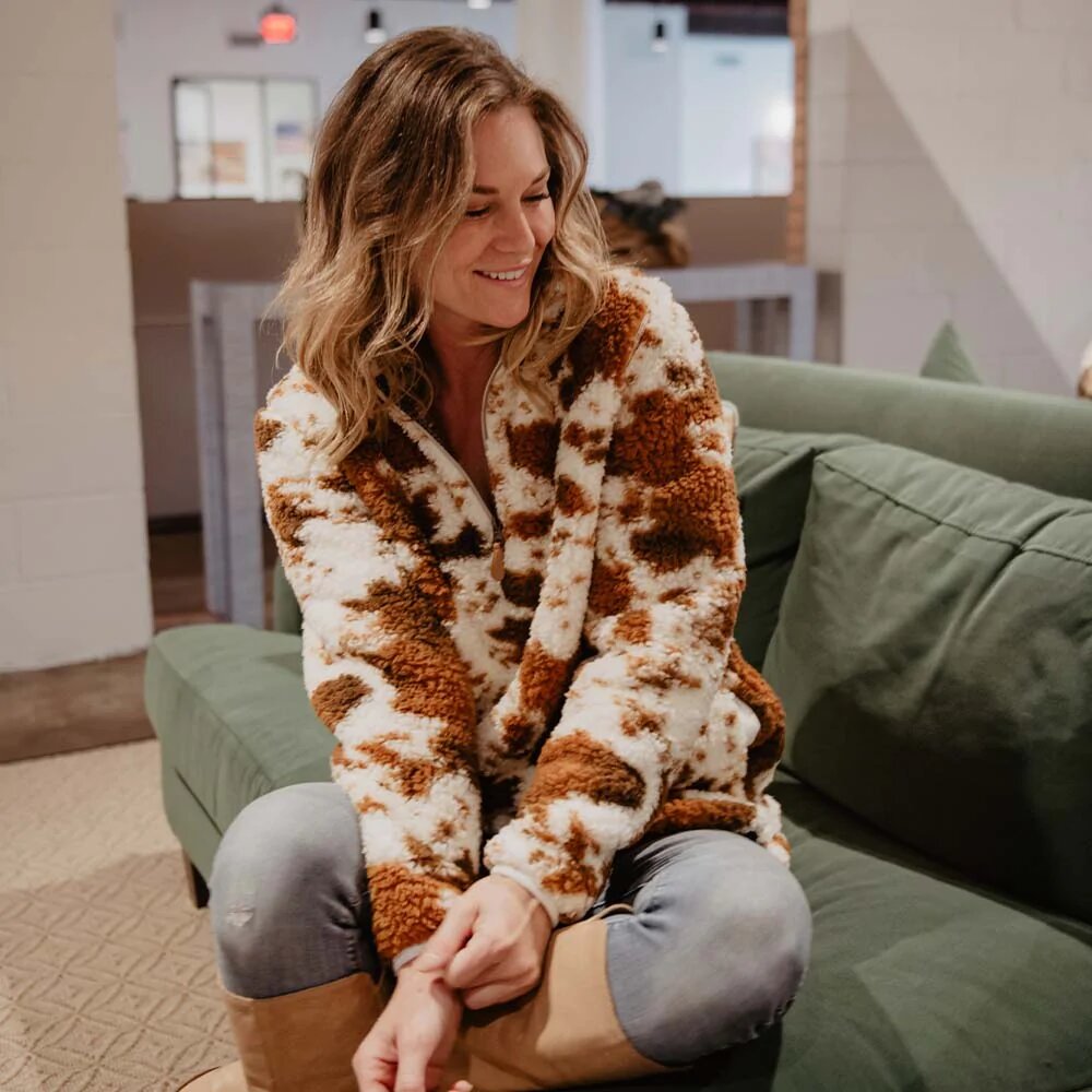Smiling woman on a sofa in brown cow print pullover