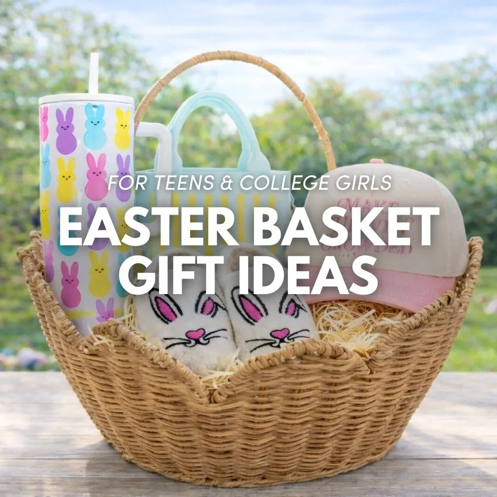 Easter basket gift ideas for teens and college girls featuring a bunny print tumbler, striped mini tote bag, bunny slippers, and a pink trucker hat in a rattan basket outdoors.