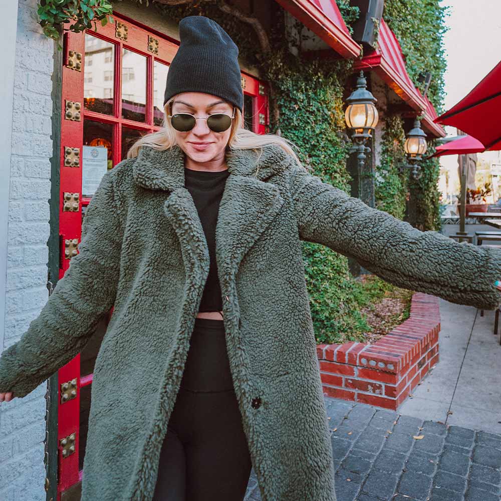  woman wearing a long green teddy jacket and black loungewear