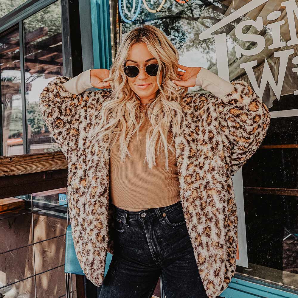 woman wearing leopard print body wrap and black skinny jeans