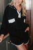 A woman stands indoors, smiling confidently with one hand in her pocket, wearing Katydids Black  White Quarter Snap Athletic Set for women—a sporty pullover and matching black shorts trimmed with white.