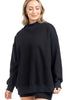 A woman with shoulder-length blonde hair smiles with her eyes closed, wearing the Katydid Black Mockneck Sweatshirt and black shorts against a white background.