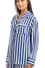 A woman stands and smiles slightly, wearing the Katydid Light Blue and Navy Striped Satin Pajama Matching Set with long sleeves and a chest pocket.