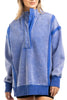 A person wears the Katydid Blue Vintage Wash Snap-Neck Pullover featuring a high snap-button collar, exposed seam details, and an oversized fit, paired with black shorts.