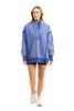 A woman wears the Katydid Blue Vintage Wash Snap-Neck Pullover with black shorts and white sneakers, standing and smiling while looking slightly to the side against a white background.