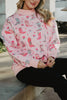 A woman sits on a concrete bench wearing the Katydid Boots  Roses Printed Sweatshirt, which features colorful cowboy boots and floral patterns, paired with black pants.