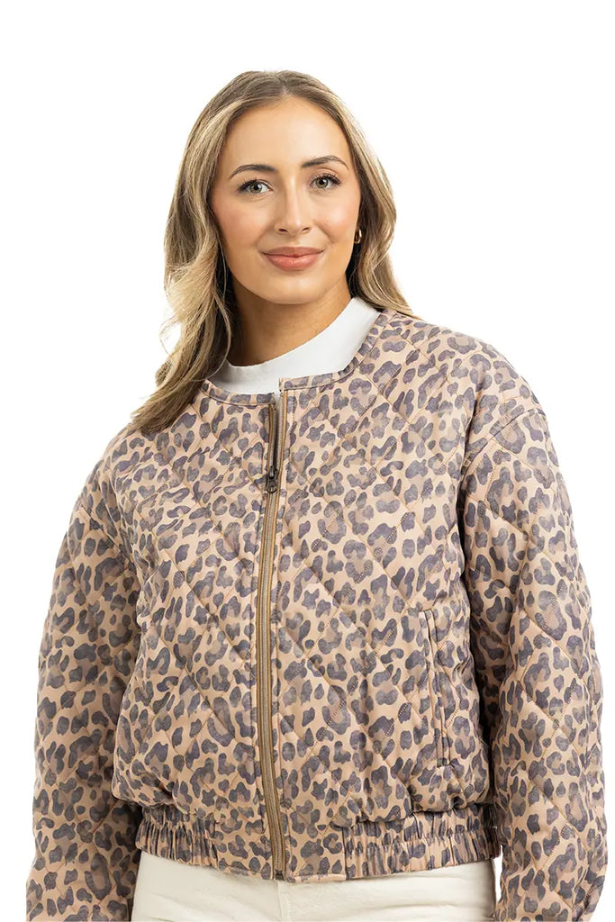 A woman with long, wavy blonde hair models the Katydid Brown Leopard Quilted Jacket over a white top, standing against a plain white background.
