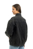 A woman with straight brown hair poses in the Katydid Womens Charcoal Luxe Oversized Jacket and light blue jeans, showcasing the jackets diamond quilting and relaxed vintage-inspired style against a white background.