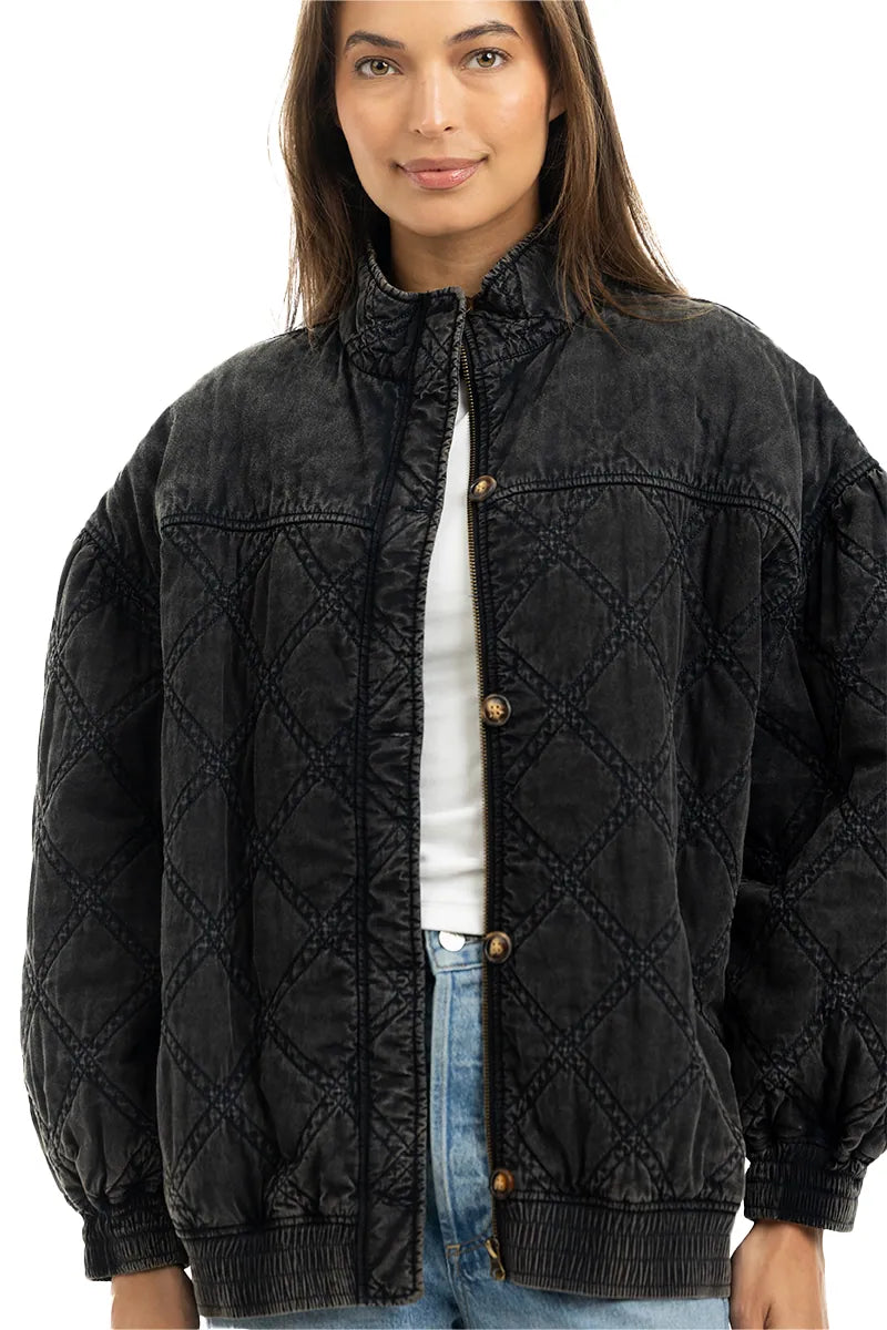 A woman wearing the Katydid Womens Charcoal Luxe Oversized Jacket stands facing the camera with a slight smile, pairing it with a white top and blue jeans.