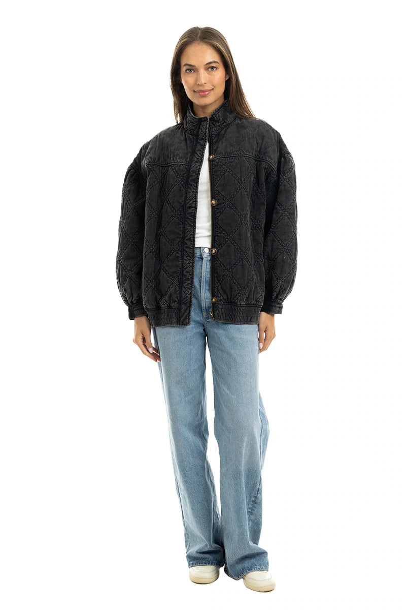 A woman faces forward in a Katydid Womens Charcoal Luxe Oversized Jacket, light blue jeans, white top, and white sneakers. She has straight shoulder-length brown hair and a neutral expression, against a plain white background.
