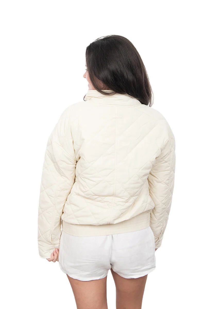 Person wearing a cream-colored puffer jacket and white shorts on a white background