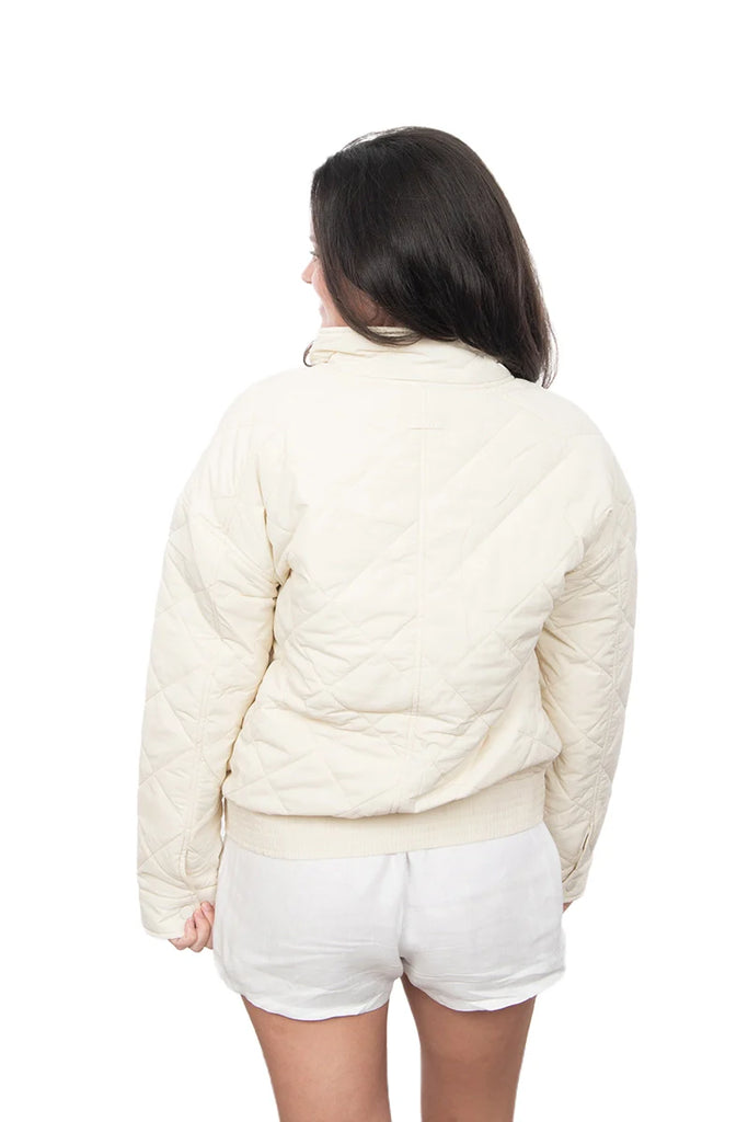 Person wearing a cream-colored puffer jacket and white shorts on a white background