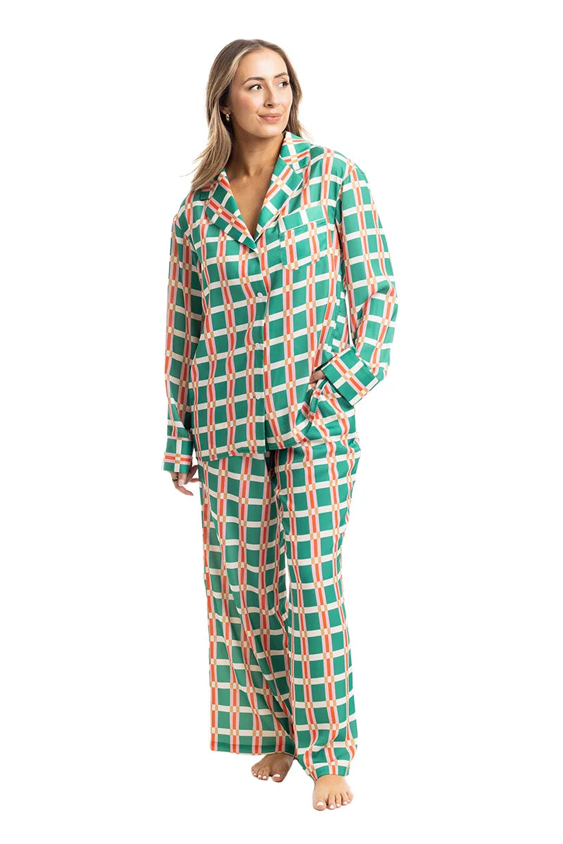 A woman stands barefoot against a white background, smiling to the side in the Katydid Green  Pink Plaid Pajama Pants Set—an ideal choice for cozy comfort.