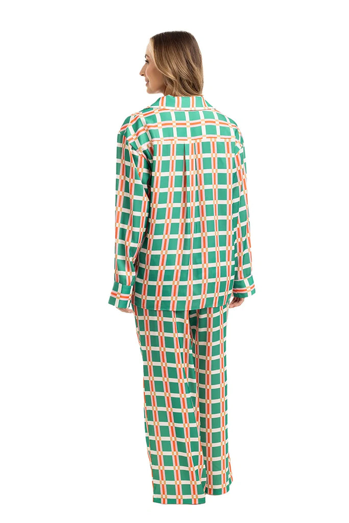 A woman faces away, wearing the Katydid Green  Pink Plaid Pajama Pants Set. The loose-fitting women’s pajama set features a matching plaid pattern that complements her shoulder-length light brown hair.