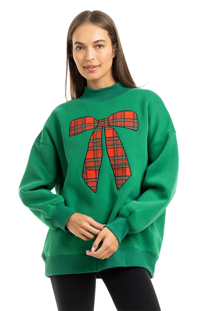 A woman smiles against a white background wearing the Katydid Red Plaid Bow Mockneck Sweatshirt for women, creating a cozy holiday outfit.