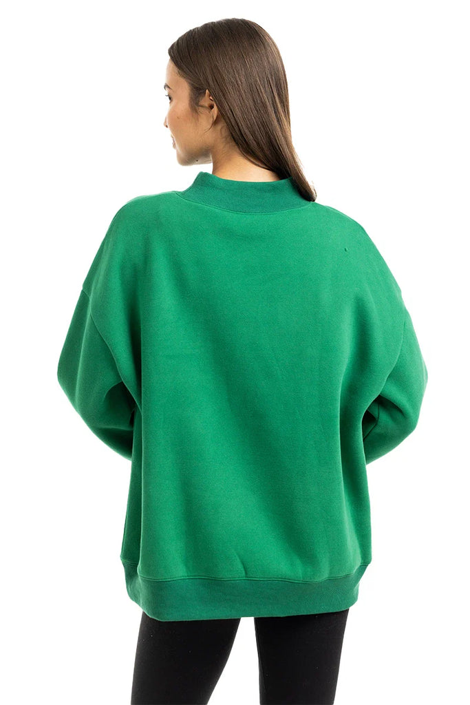 A woman with long brown hair, seen from behind, wears the Katydid Red Plaid Bow Mockneck Sweatshirt for women and black pants against a plain white background—a perfect cozy holiday look.