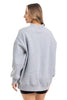 A woman with long, light brown hair wears the Katydid Heather Essential Mockneck Sweatshirt in heather gray, paired with black shorts. She stands against a white background—showcasing this cozy pullover perfect for fall.