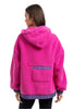 A person with long brown hair is seen from behind wearing the Katydid Hot Pink Two-Toned Sherpa Pullover Jacket, which features cozy purple trim and a purple lower back pocket.