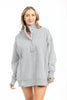 A woman with light brown hair smiles gently at the camera, wearing the Katydid Gray Vintage Wash Pullover Jacket featuring an oversized fit, snap-neck collar, long sleeves, and side slits against a white background.