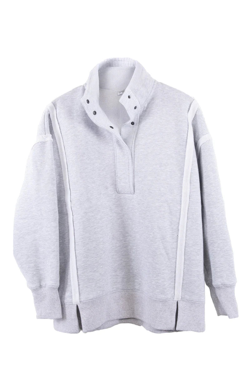 The Katydid Gray Vintage Wash Pullover Jacket features long sleeves, a high snap-neck collar, white accent stripes on the shoulders and sides, ribbed cuffs and hem, plus side slits for a relaxed fit.