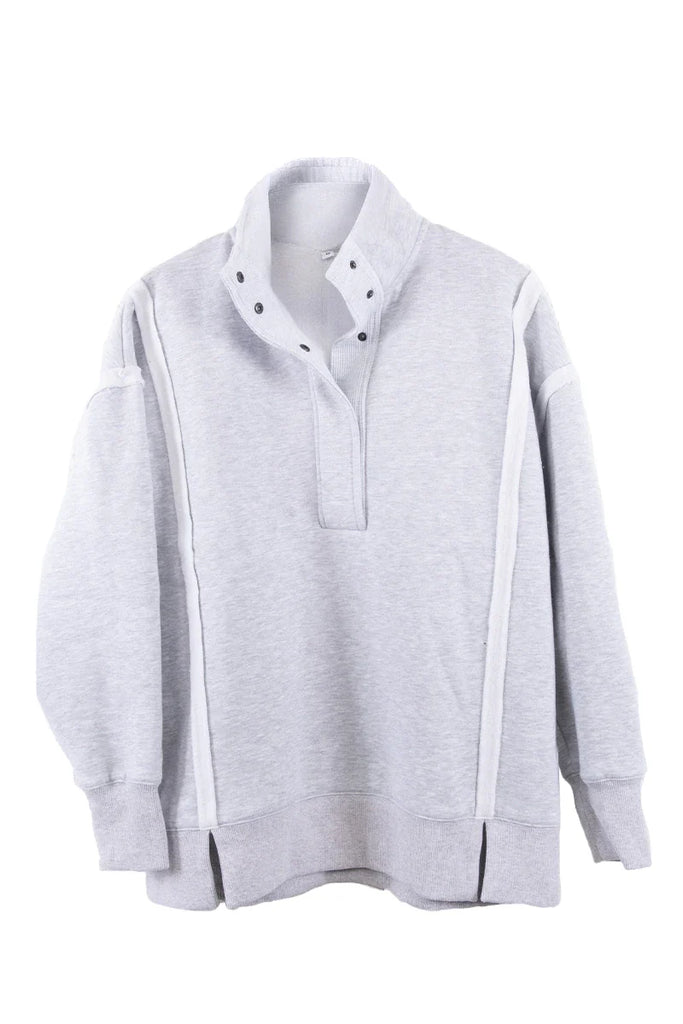 The Katydid Gray Vintage Wash Pullover Jacket features long sleeves, a high snap-neck collar, white accent stripes on the shoulders and sides, ribbed cuffs and hem, plus side slits for a relaxed fit.