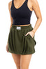 A woman models the Katydid Olive Athletic Skirt for Women, a trendy olive green skirt with pockets, an elastic waistband, and a visible Katydid label on the front.