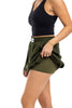 A woman wearing a black sleeveless top and Katydids Olive Athletic Skirt for Women lifts one side to display a label on the waistband. Her face is not shown.