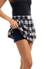 A person in a black top lifts the Katydid Blue Autumn Plaid Skirt to reveal built-in shorts underneath. The photo highlights their waist and legs against a white background.