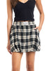 A person wears a sleeveless black top and the Green Autumn Plaid Skort by Katydid, featuring handy pockets and the brand’s label on the waistband. Its classic green plaid design makes it a perfect fall piece.