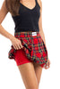 A woman in a black tank top lifts a Katydid Royal Stewart Plaid Mini Bubble Skirt, revealing red fitted shorts underneath. The classic pattern makes this festive look perfect for a Christmas party against a crisp white background.