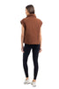 A woman faces away, wearing the Katydid Brown Corduroy Quilted Vest over a sleeveless top with black leggings and white sneakers—a stylish fall outfit set against a white background.