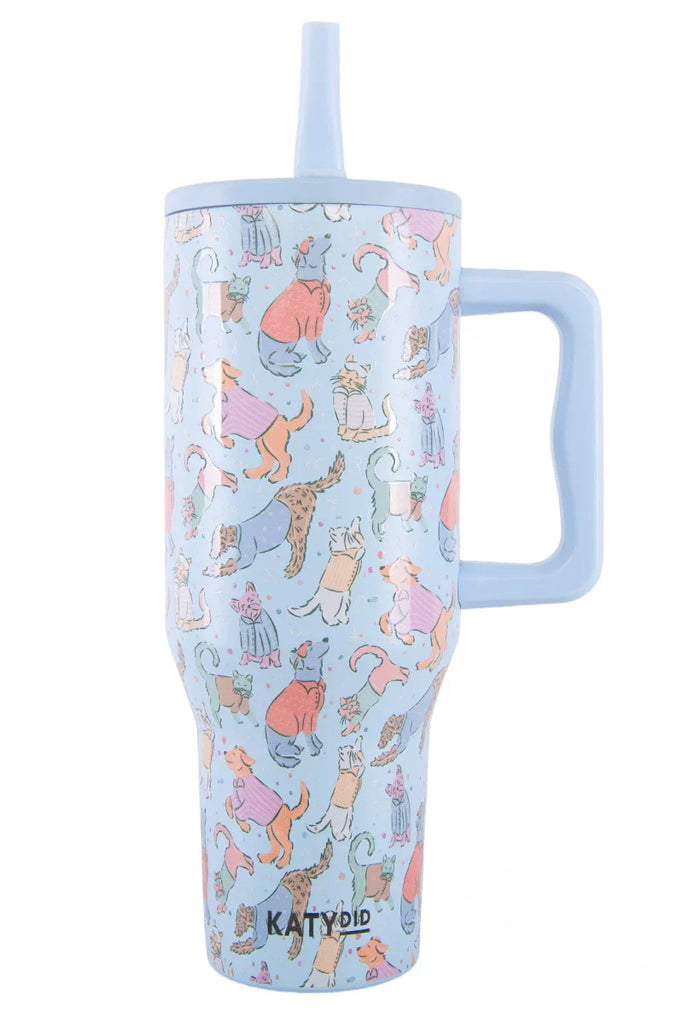 The Katydid Posh Pets Party Easy Carry Flip Top Tumbler is a light blue reusable cup with a large handle, straw, and playful dog illustrations in colorful outfits.