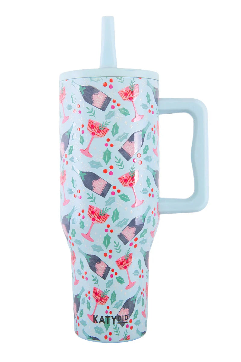 The Katydid Holiday Champagne Cheerful Design Flip Top Tumbler is light blue with a handle, straw, and festive wine glass and holly designs. Spill-proof and stylish, its the perfect travel cup for holiday celebrations.