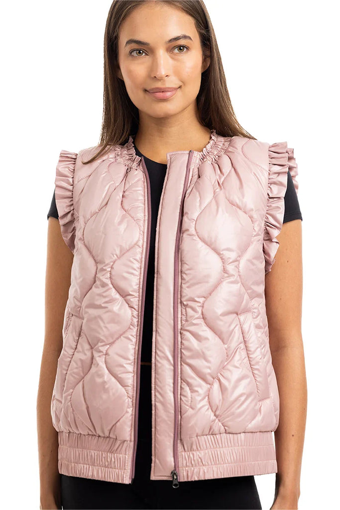 A woman smiles with her hair down, wearing the Katydid Blush Metallic Puffy Vest over a black short-sleeve top for a fresh, feminine look.