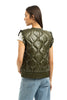 A woman with straight brown hair, facing away from the camera, wears the Katydid Olive Metallic Puffer Lightweight Vest over a white top and light blue jeans.