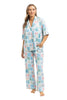 A woman models Katydids Book Club Matching Pajama Sets—light blue pants and a short-sleeve top with pastel book cover prints—standing barefoot against a white background.