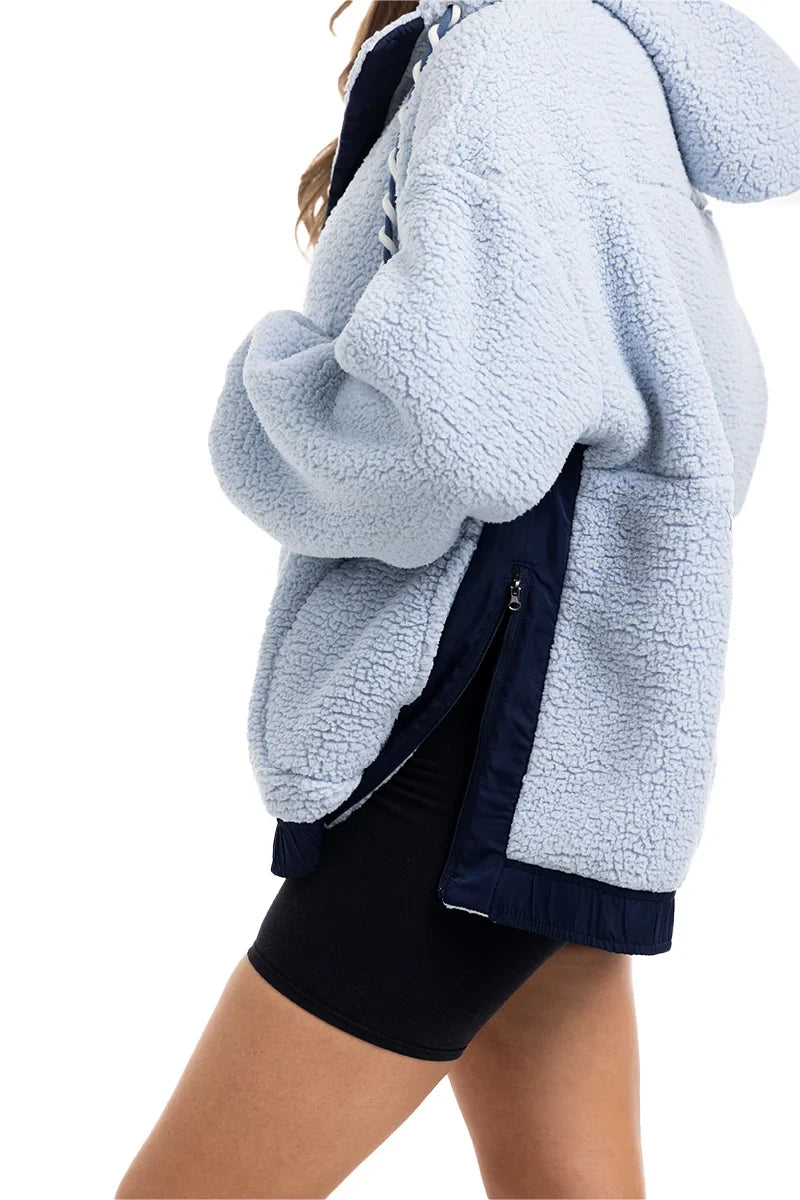 A person wearing the Katydid Light Blue Two-Toned Sherpa Fleece Pullover with dark trim and black shorts, shown from the shoulders down against a white background.