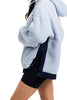 A person wearing the Katydid Light Blue Two-Toned Sherpa Fleece Pullover with dark trim and black shorts, shown from the shoulders down against a white background.