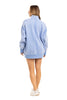 A woman faces away against a white background, wearing the Katydid Light Blue Vintage Wash Snap-Neck Pullover, which falls to mid-thigh, paired with white sneakers. She has light brown hair.
