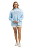 A woman smiles in the Katydid JESUS Mockneck sweatshirt, paired with white shorts and sneakers—a stylish pick for Christian apparel—set against a simple white background.