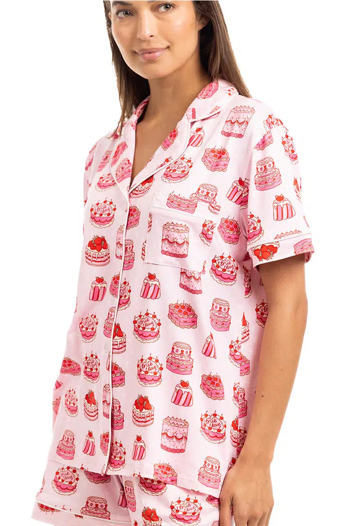 A woman models the Katydid Girly Cakes PJ Shorts Set, featuring light pink short sleeves and shorts with a playful cake print—perfect for those who love fun, girly pajamas.