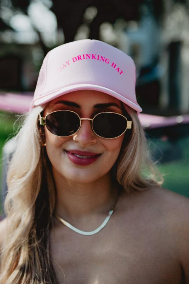 A woman wearing a pink day drinking hat and sunglasses