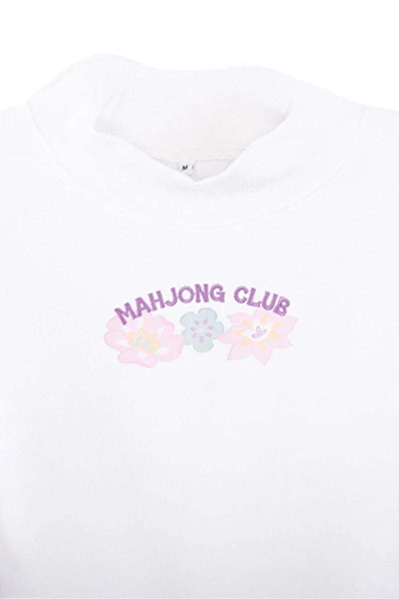 The Katydid Mahjong Club Mockneck Pullover features MAHJONG CLUB in purple above pastel flowers and a green tile—perfect for game night with friends.