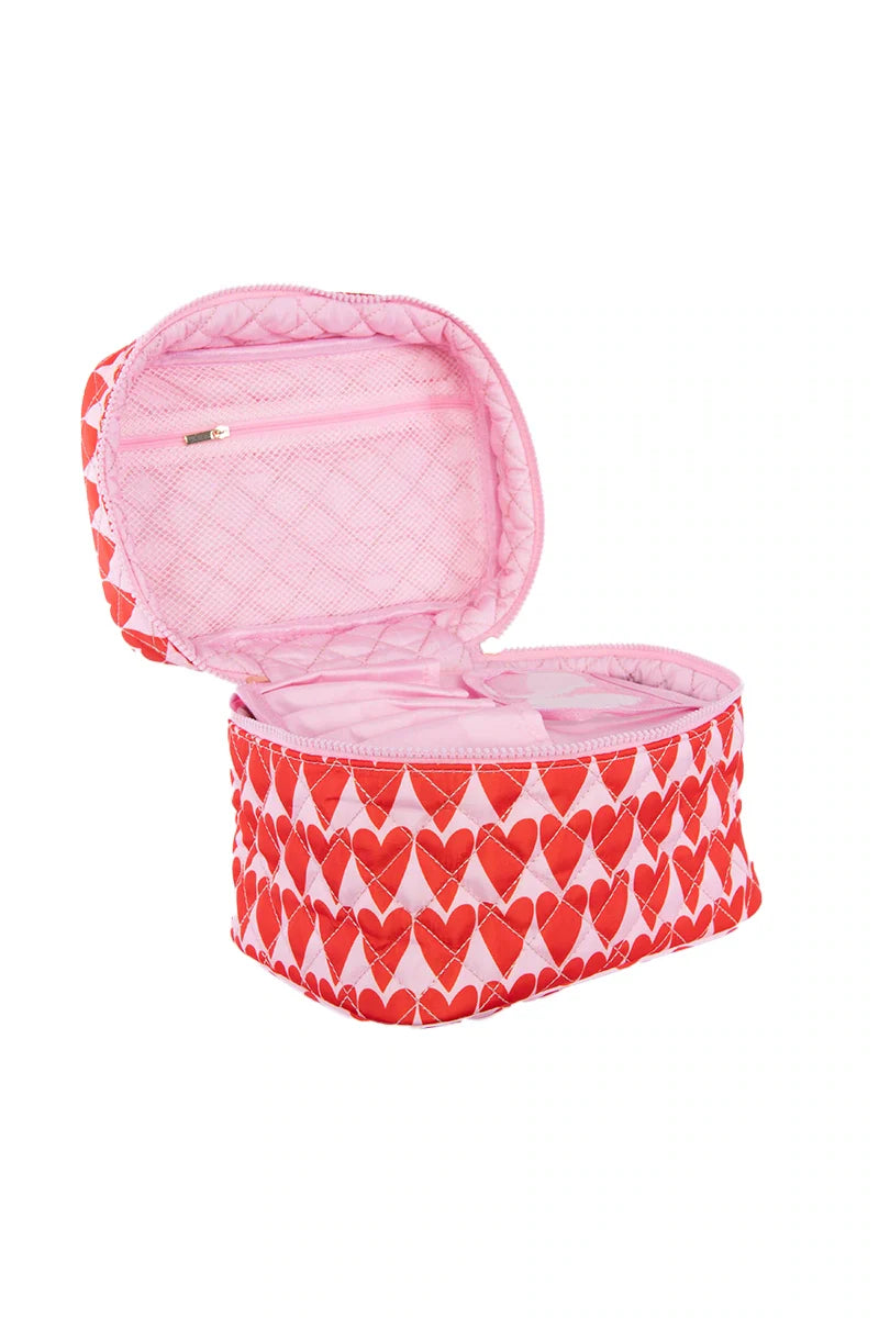 The Katydid Girly Red Hearts Makeup Bag features pink quilted fabric with red hearts, an open lid with a zippered pocket, and a roomy main compartment—ideal for organizing your beauty essentials.