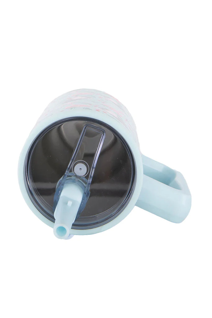 The Katydid Holiday Champagne Cheerful Design Flip Top Tumbler is a light blue, spill-proof travel cup with a handle and a dark transparent lid featuring a spout and flip-up cover, shown from above.