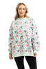 A person wears the Katydid Holiday Champagne, Coupes  Holly Mockneck Sweatshirt, standing with hands relaxed by their sides and smiling at the camera against a white background.