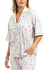 A woman models the Katydid Mahjong Pieces Pajama Pants Set, a light-colored, short-sleeve collared set with buttons and a playful pastel Mahjong pattern. She accessorizes with bracelets, adding charm to these cute pajamas.