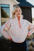 A woman smiles with her hands on her hips outside a house, wearing the Katydid Confetti Print Womens Pullover featuring a multicolored confetti design and peach accents.