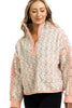 A woman wears the Katydid Confetti Print Womens Pullover, featuring a half-zip front, peach trim, and playful speckled fleece. She smiles softly with her eyes closed, her long light brown hair framing her face.