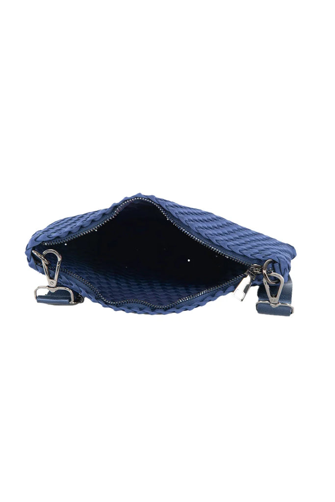 The Katydid Navy Woven Everywhere Small Crossbody is shown from above with its zippered opening wide, revealing a spacious dark interior and two metal clasps on either side for an adjustable strap.